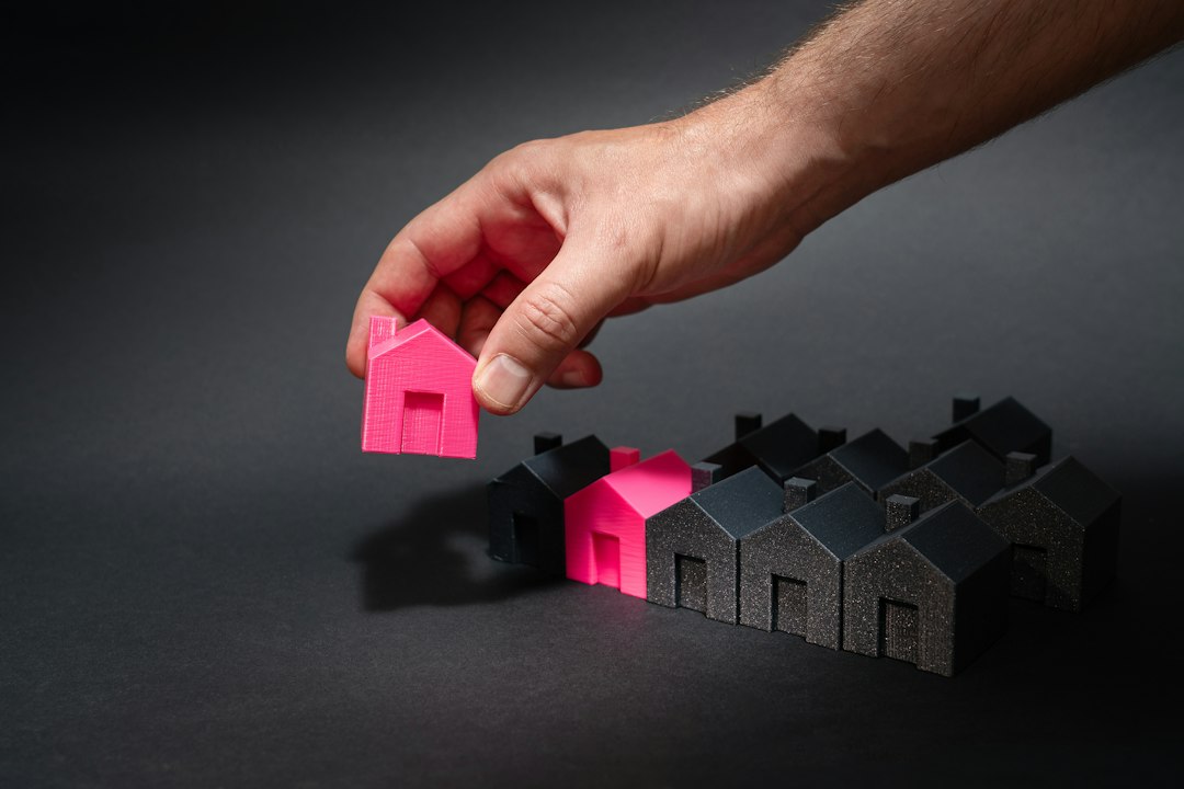 Person's hands carefully balancing two miniature house models on a scale, symbolizing the financial decision between diffe...